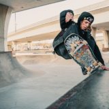 photo of man in black hoodie doing a skateboarding trick at at skate park