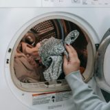anonymous woman putting clothes in washing machine